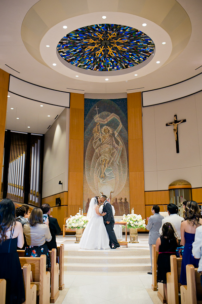 Santa Monica wedding with the bride and groom kissing at the church altar after their catholic wedding ceremony by Dallas wedding photographers.